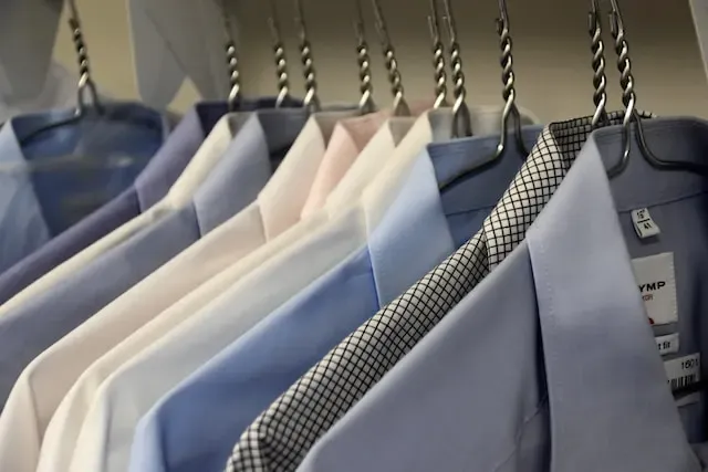 a row of ironed shirts hung up on coat hangers
